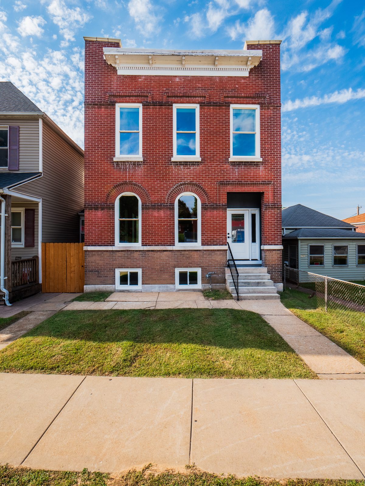 Carondelet St. Louis homes for sale — renovated 2-story red brick flat with ornate cornice and arched windows, the kind of pre-war city construction buyers find in 63116 South City Carondelet