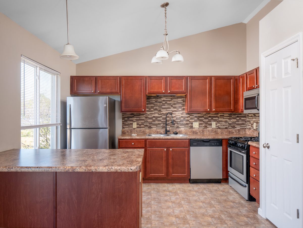 St. Louis home kitchen — cherry cabinets, stainless appliances, tile backsplash, and vaulted ceiling, representative of updated kitchens buyers find in South County and outer county St. Louis homes