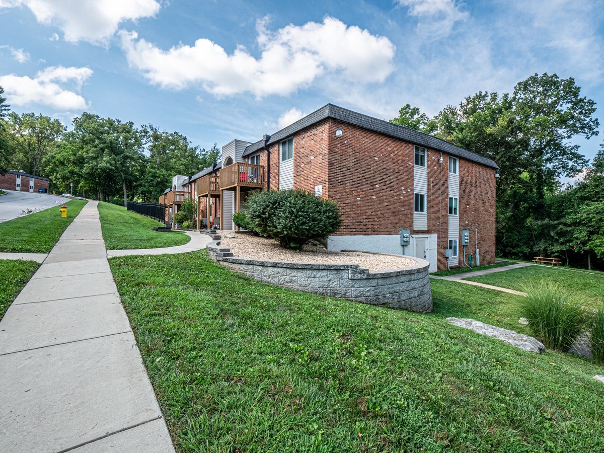 The brick condo building at 2832 Blackforest Drive, with wood balconies, a curved stone retaining wall and a sloped lawn