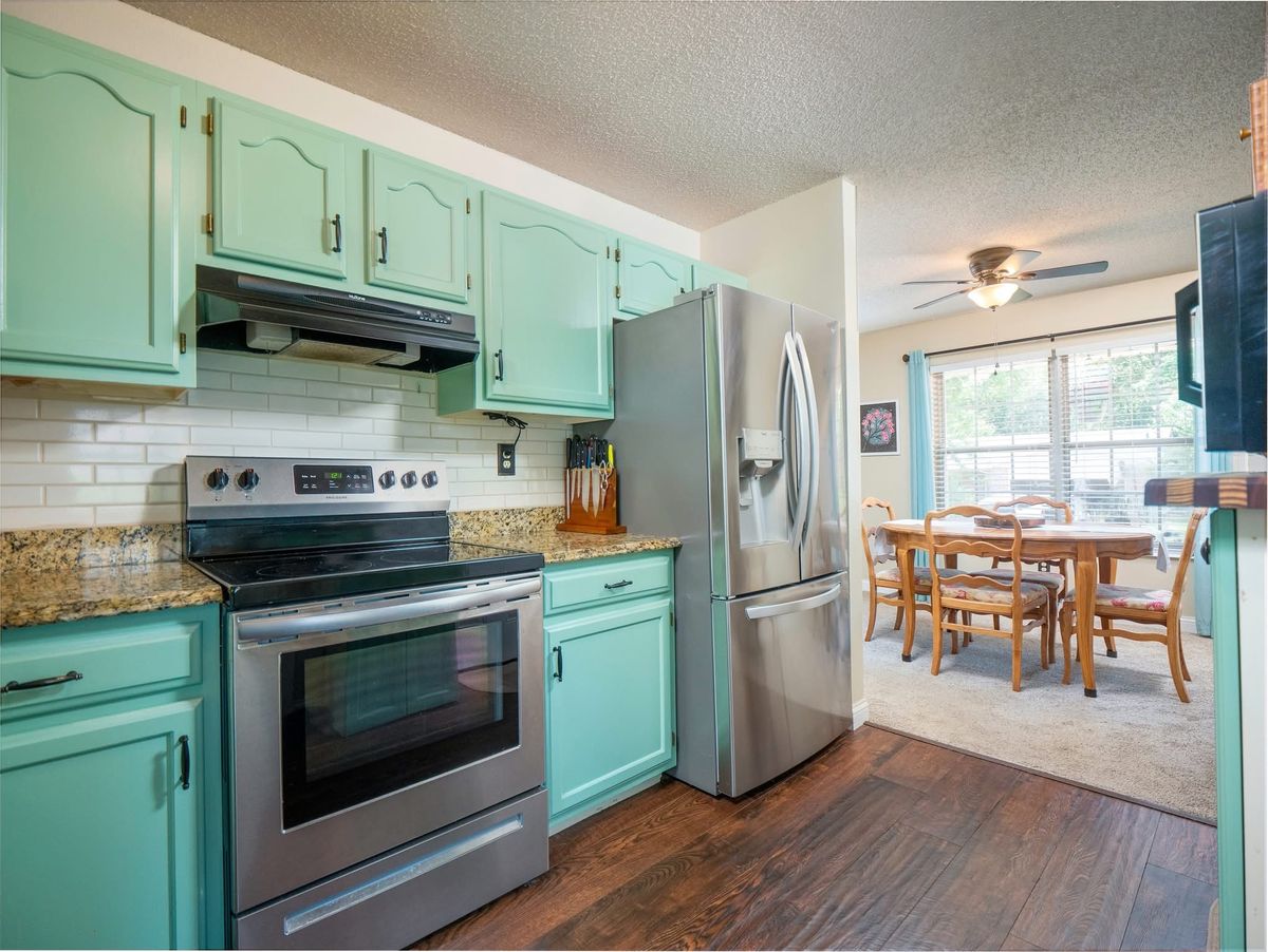 Kitchen at 5021 Galena Court with mint-green cabinets, granite counters, subway tile and stainless appliances, opening to the dining area