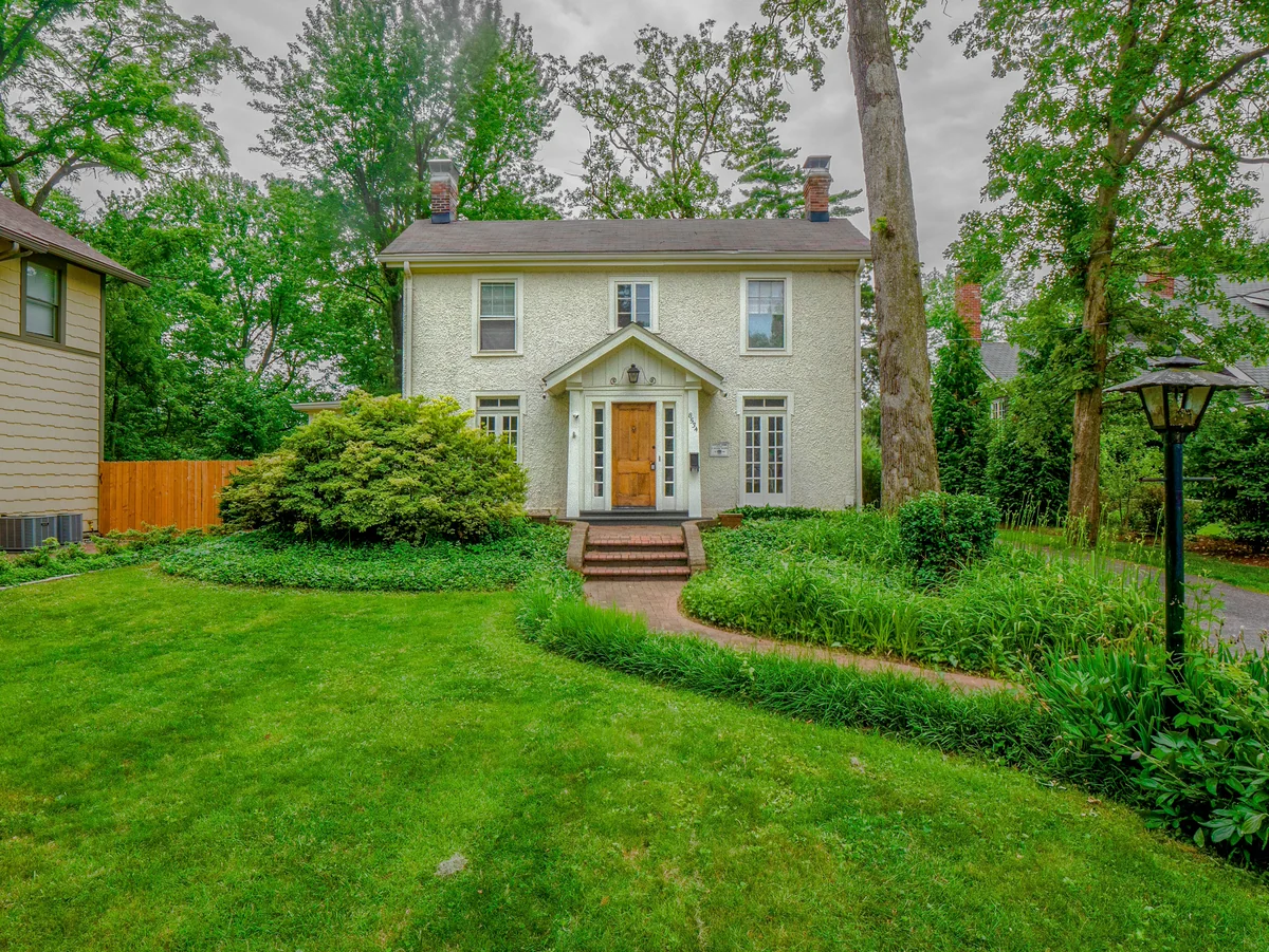 Webster Groves Missouri historic housing stock — stucco two-story home with brick walkway and mature tree canopy