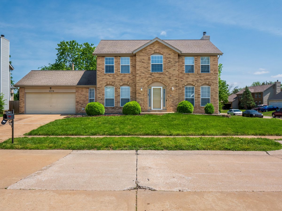 Florissant MO homes for sale — 2-story brick colonial with 2-car garage on large lot, representative of the family-sized housing stock available in 63031 North County St. Louis